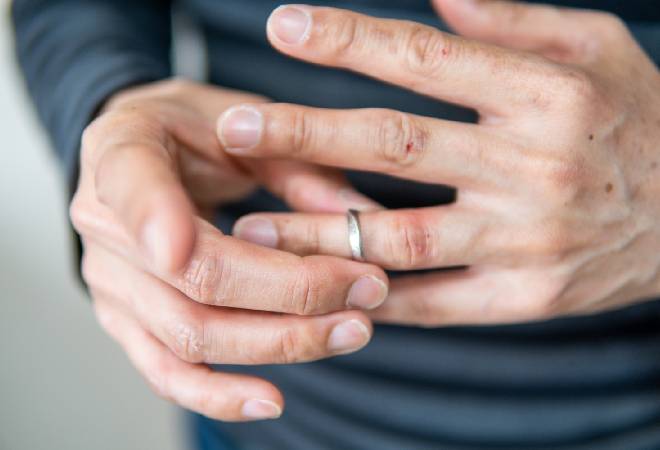 結婚指輪を外そうとしている男性の手。