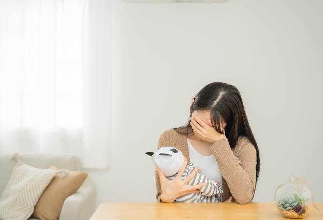 赤ちゃんを抱え項垂れる母親の姿。